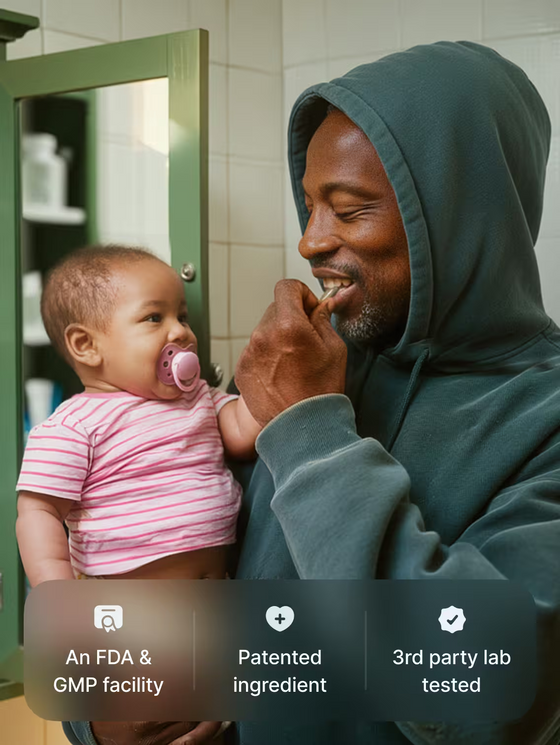 Man in a green hoodie holding a baby in a bathroom setting